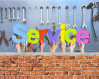 Hände halten bunte Buchstaben vor einem Werkzeugregal.