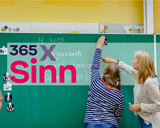 Lehrer und Schüler interagieren an einer Tafel mit Bildern.