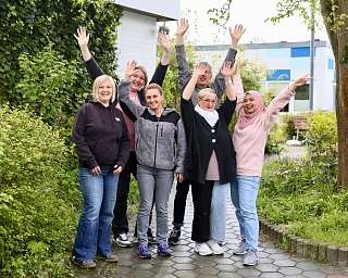 Sechs Personen posieren fröhlich im Garten.